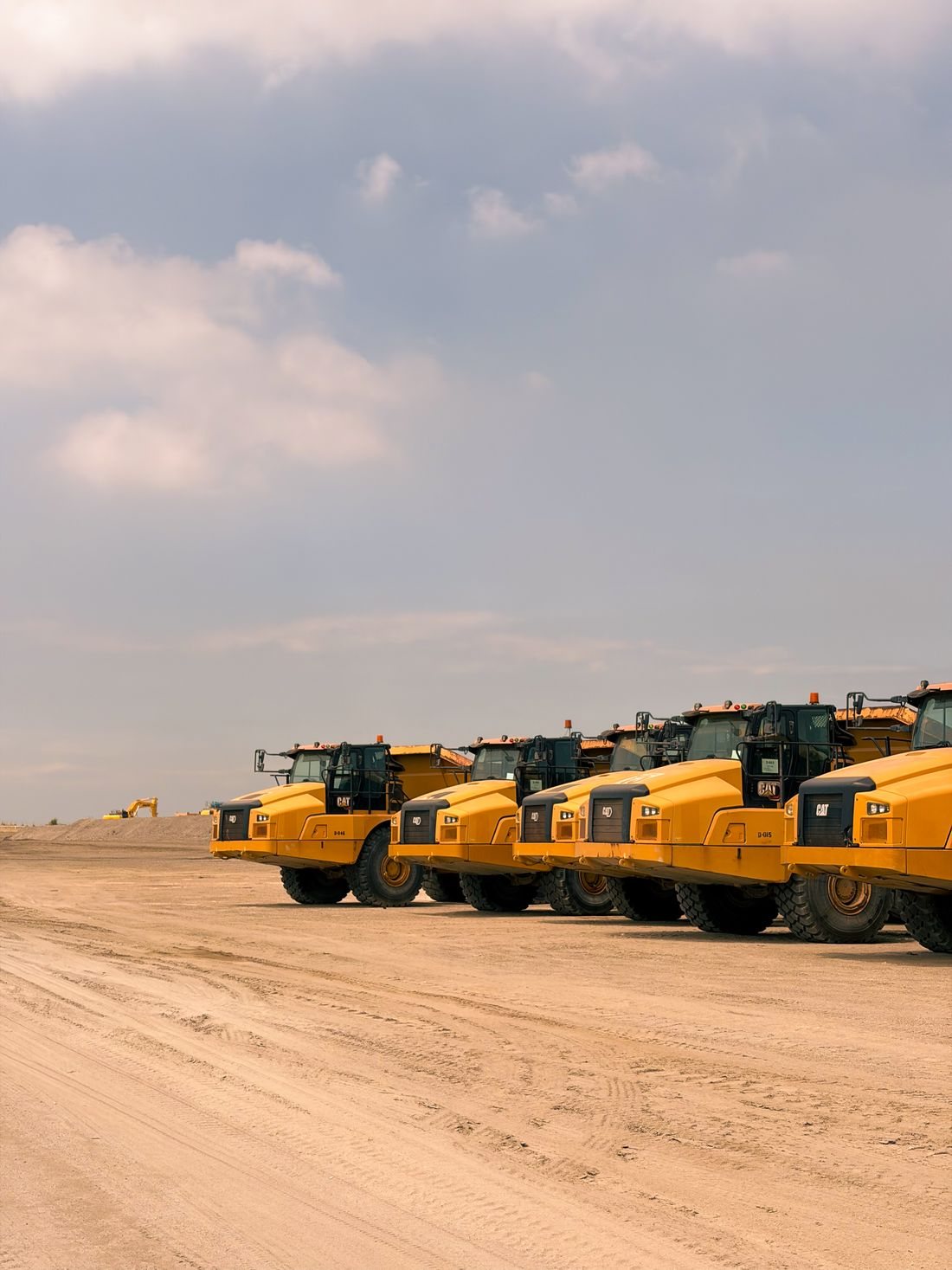 A fleet of heavy-duty haul trucks lined up, the class of machinery we bring in
